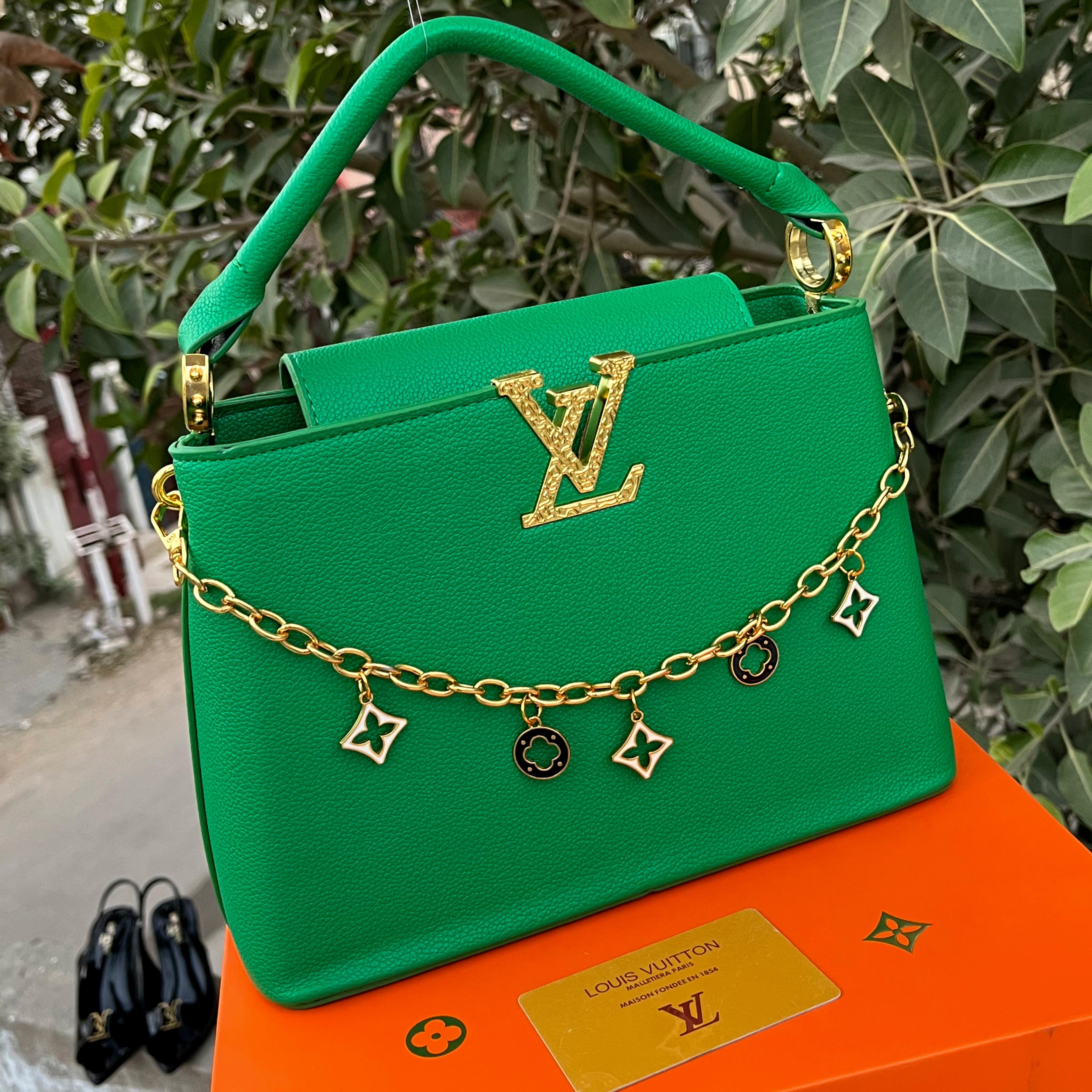 Green handbag with gold chain and charms on an orange Louis Vuitton box.
